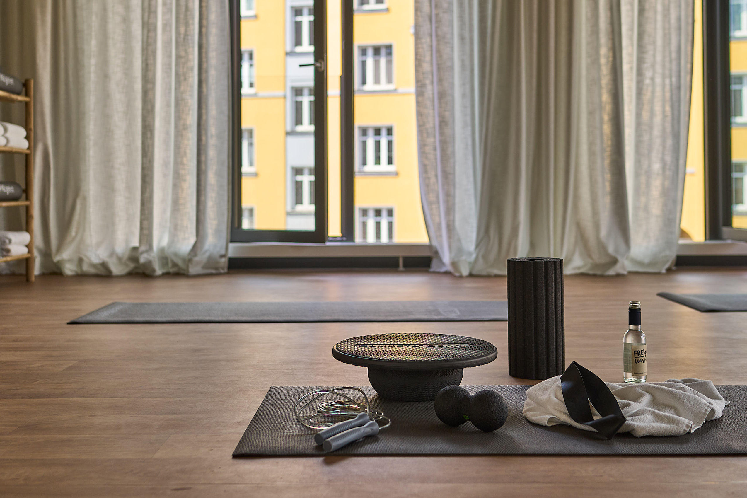 Eine Yogamatte auf dem Boden eines Fitnessraums des Hotel FREIgeist Göttingen Nordstadt mit mehreren Geräten darauf