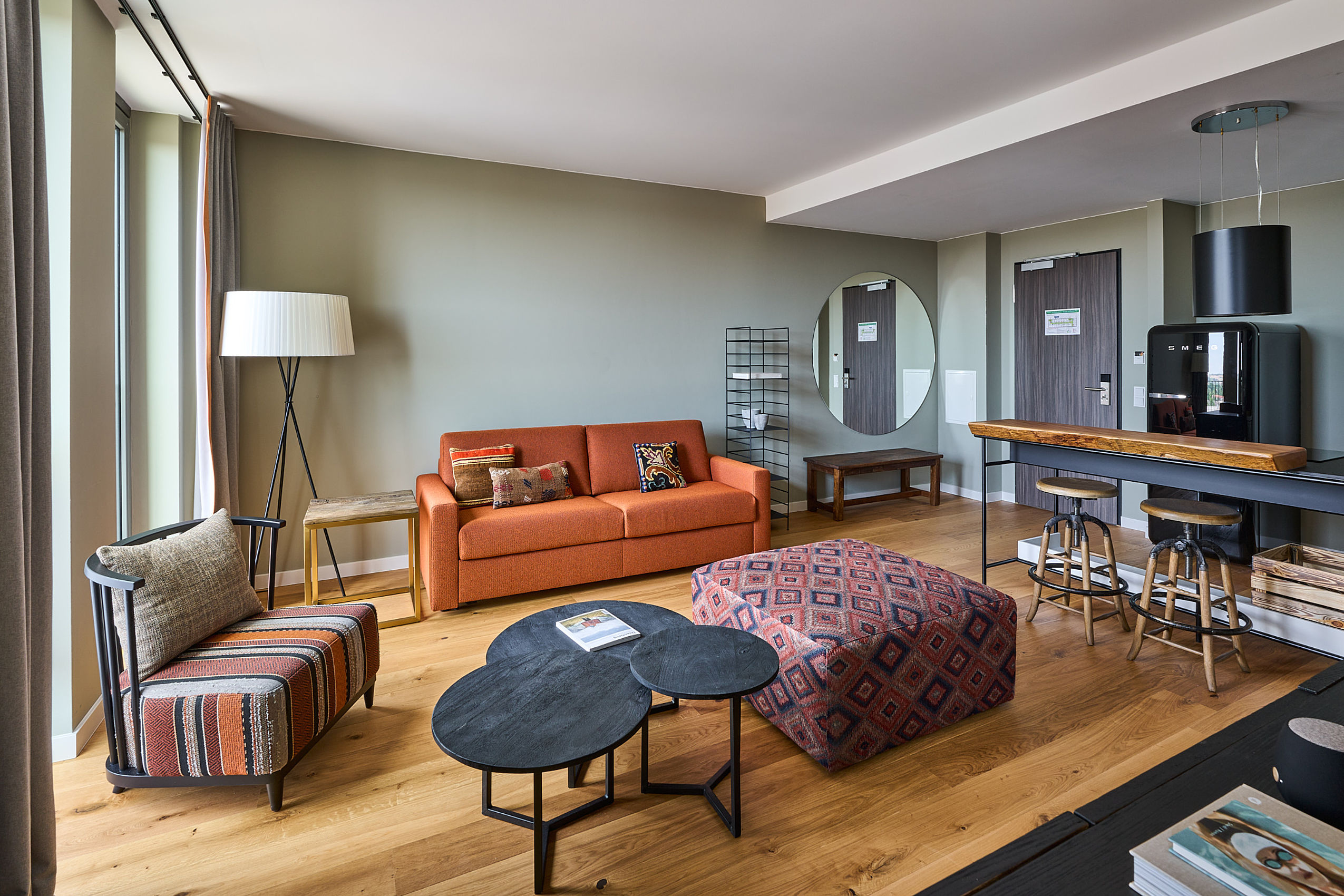 Das weite Apartment des Hotel FREIgeist mit einem orangenen Sofa und einer kleinen Truhe