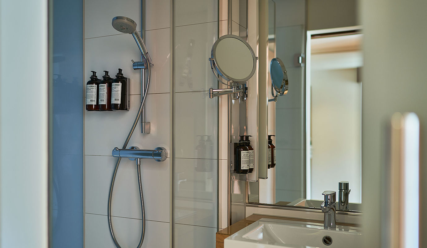 Ein Duschkopf hängt neben einem großen Spiegel