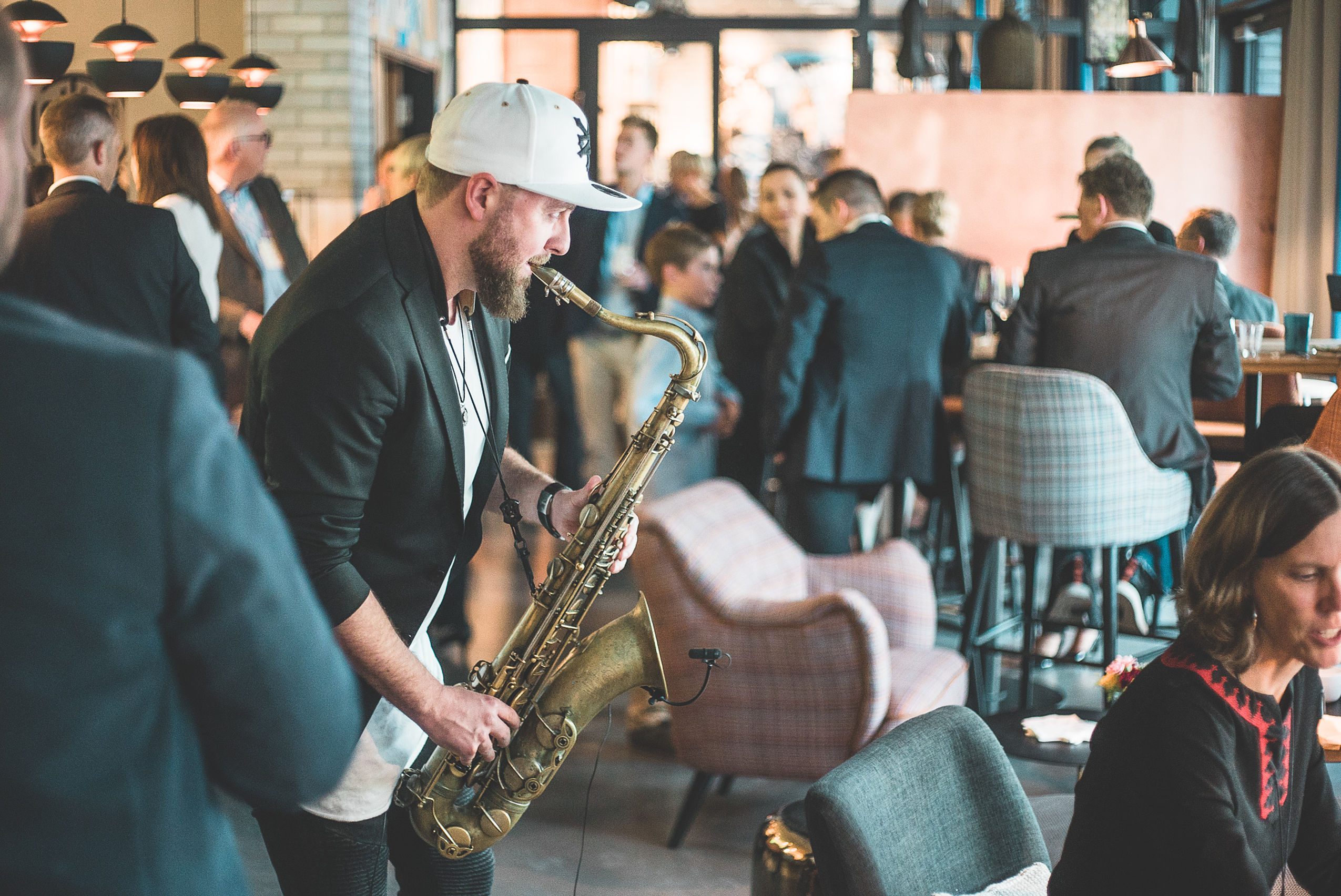 Ein Mann spielt Saxophon inmitten vieler Menschen im Hotel FREIgeist Göttingen Innenstadt