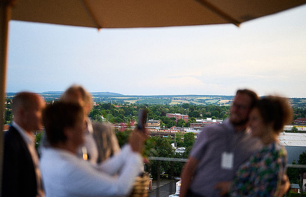Verschwommene Menschen auf der Terrasse beim Fotografieren und im Fokus die schöne Aussicht
