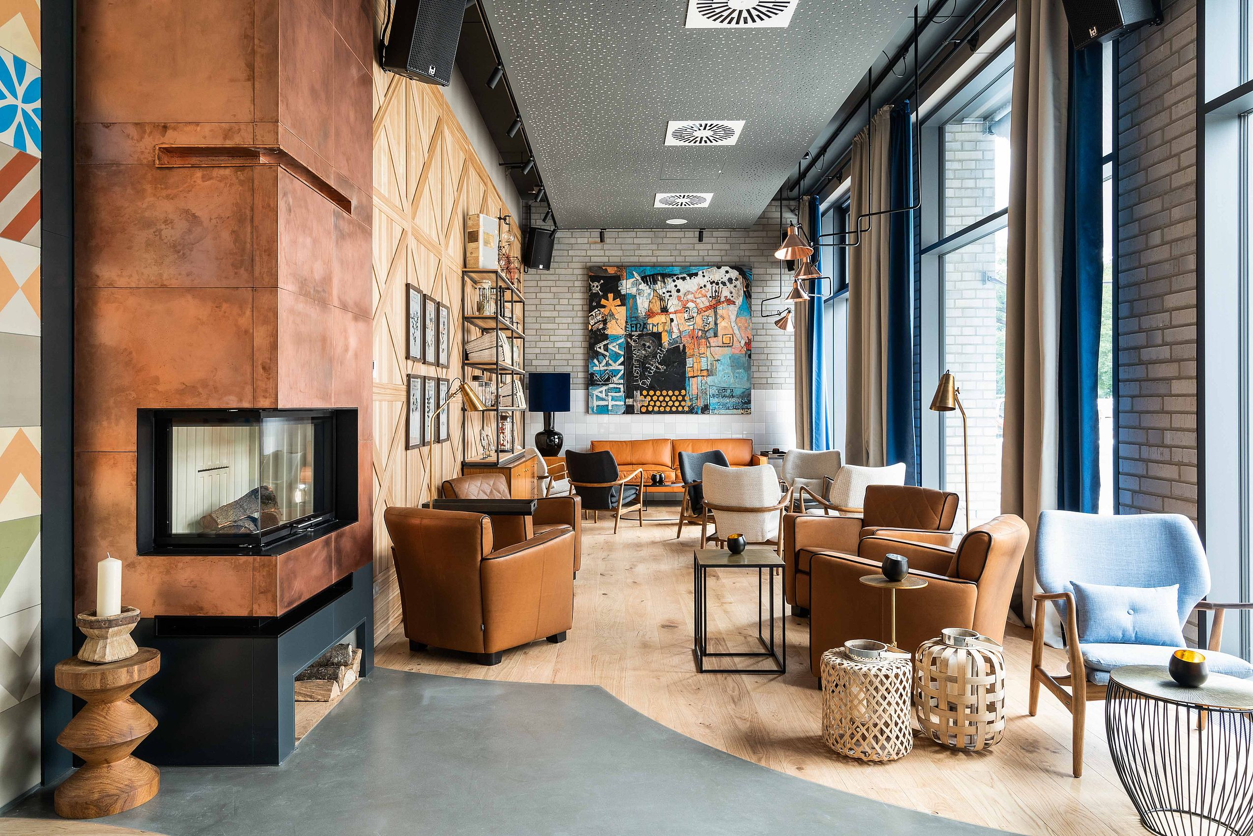 Die gemütliche und modern eingerichtete Lobby des Hotel FREIgeist Einbeck mit braunen Sesseln und großen Fenstern