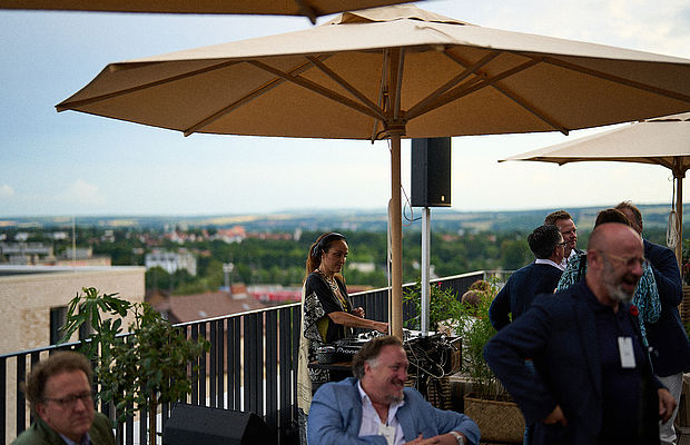 Menschen bei einer Party auf der Dachterrasse im Sommer, die sich miteinander unterhalten