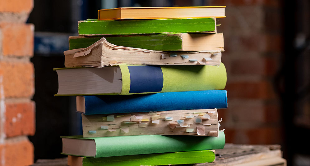Gestapelte Bücher vor einer roten Mauer