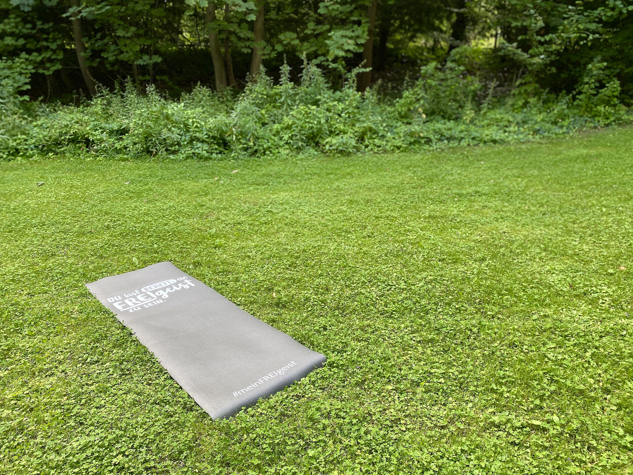 Eine Yogamatte mit der Aufschrift des FREIgeist Hotels auf einer grünen Wiese