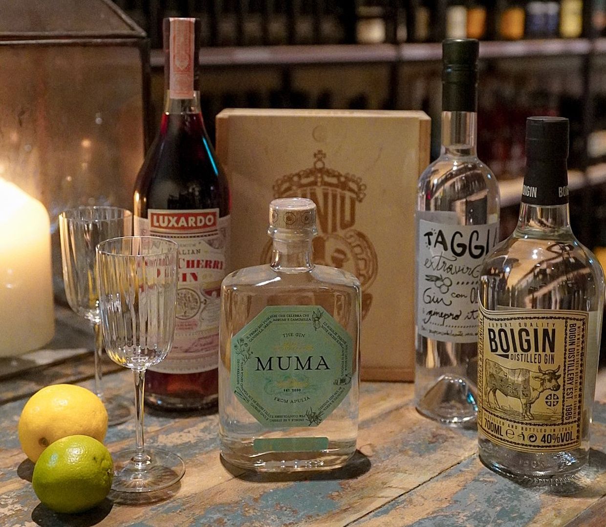 Verschiedene Gin-Sorten des Viani Alimentari auf einem Holztisch neben einer Kerze 