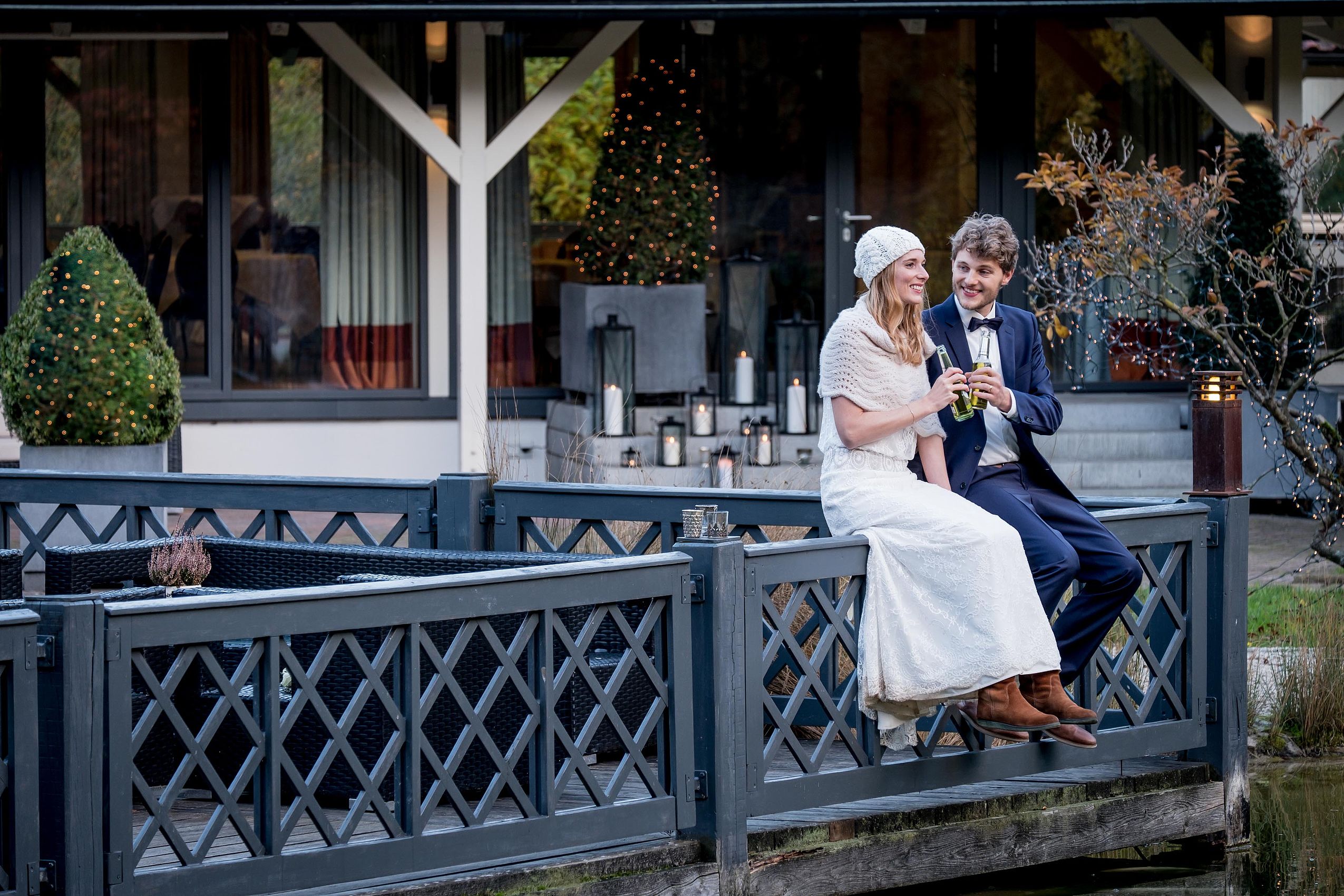 Ein Ehepaar sitzt auf dem Geländer einer Brücke und stößt mit Sektgläsern an