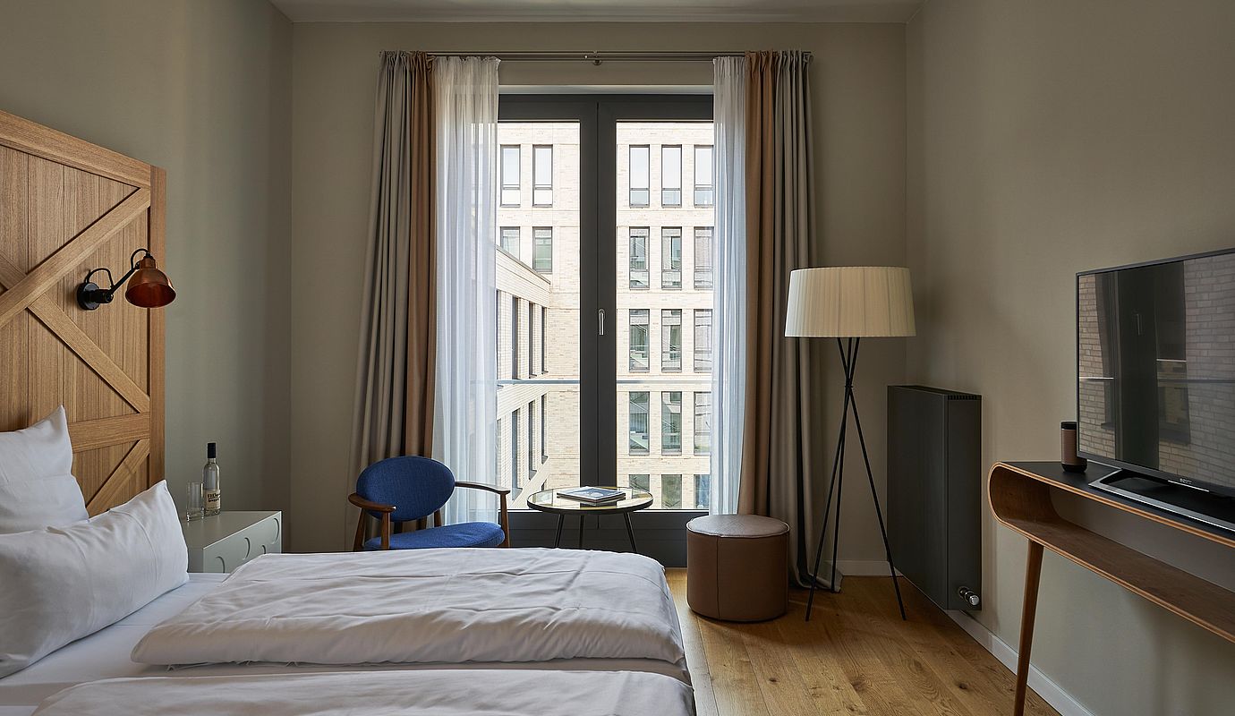 Ein helles Hotelzimmer mit großem Fenster und einem frisch gemachten Bett